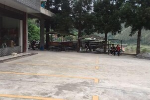 Un estacionamiento con espacios delimitados, una zona de estar techada y un edificio con amplios ventanales.