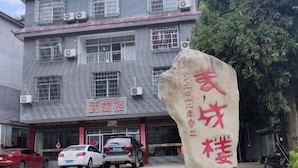 Un edificio con un letrero que dice “三丰楼” y una gran piedra con texto rojo.