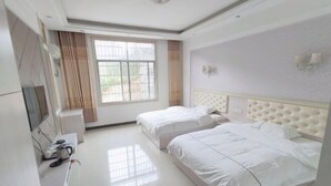 Habitación de hotel con dos camas, televisión y ventana con cortinas.