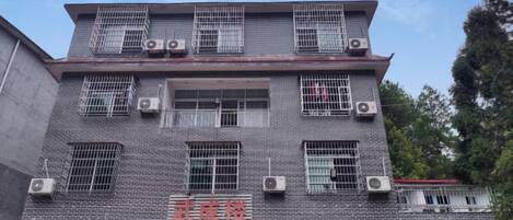 Un edificio de varios pisos con fachada de tejas, numerosas ventanas y unidades de aire acondicionado.