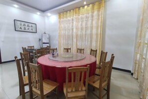 A conference room with a round table, wooden chairs, a red tablecloth, a whiteboard, and a water dispenser. - Shuangpai Wuchenglou Hotel (Shuangpai)