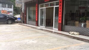 Un edificio con un estandarte rojo, un perro acostado en el suelo y un coche aparcado.
