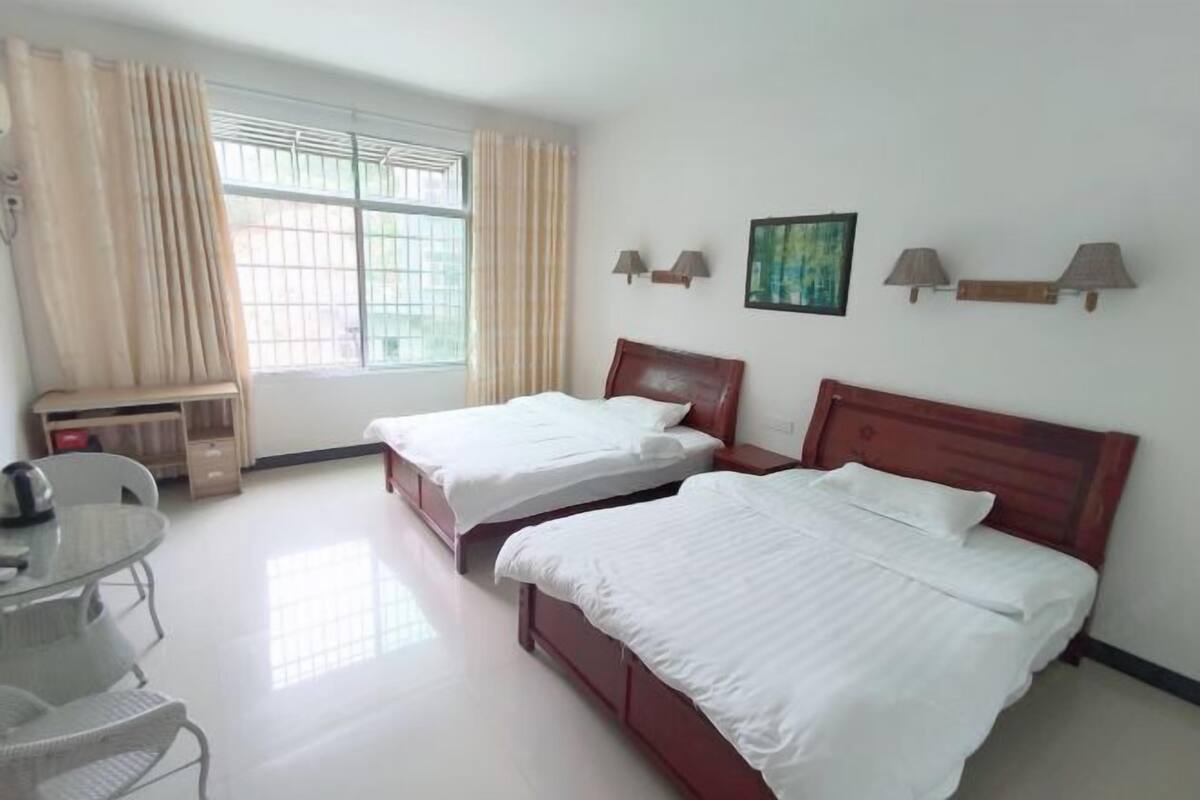 A hotel room with two beds, a desk, and a window with curtains.