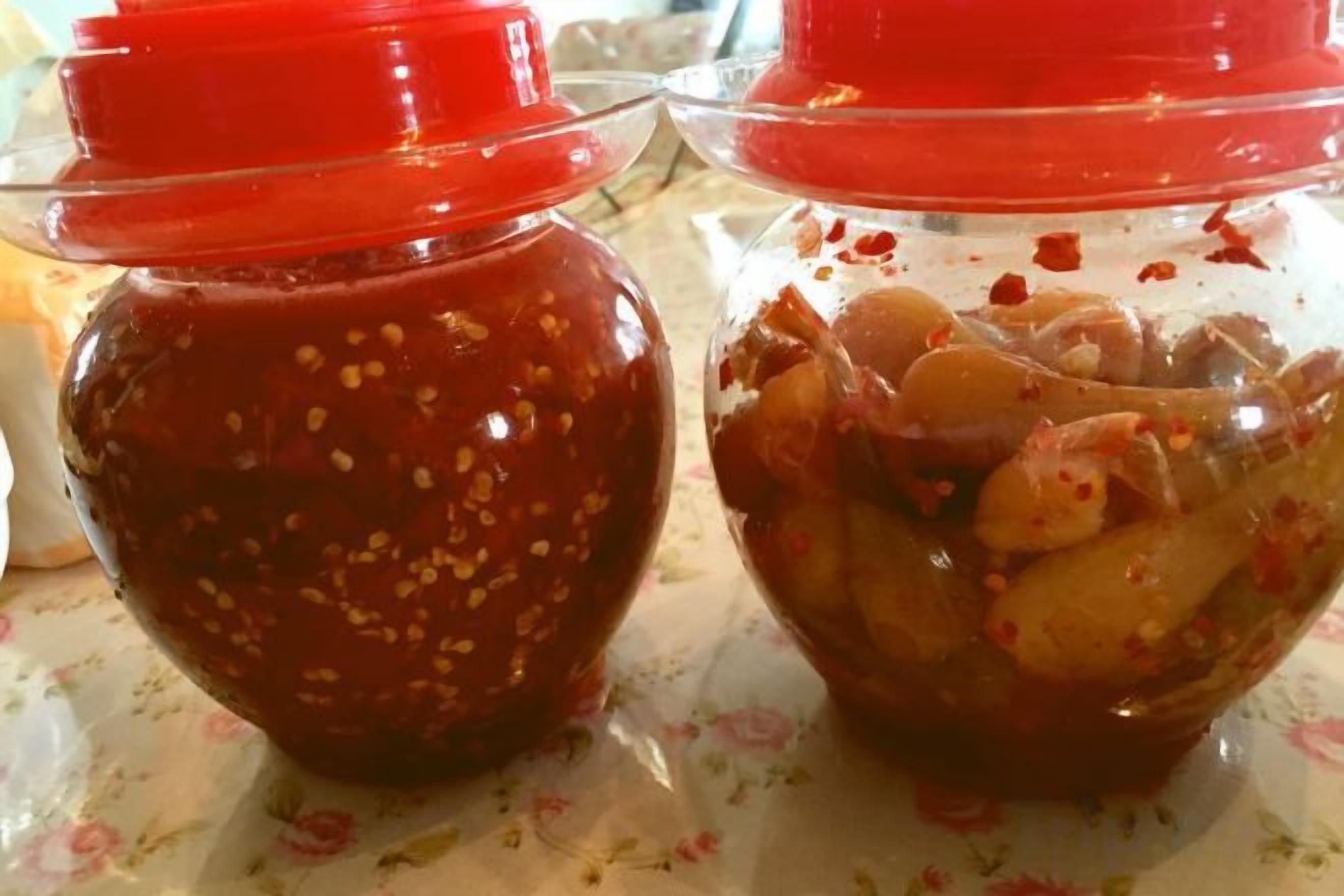 Due barattoli di vetro con tappi rossi, uno contenente una salsa rosso scuro con semi visibili e l'altro con una salsa rossa più chiara e pezzi di cibo.