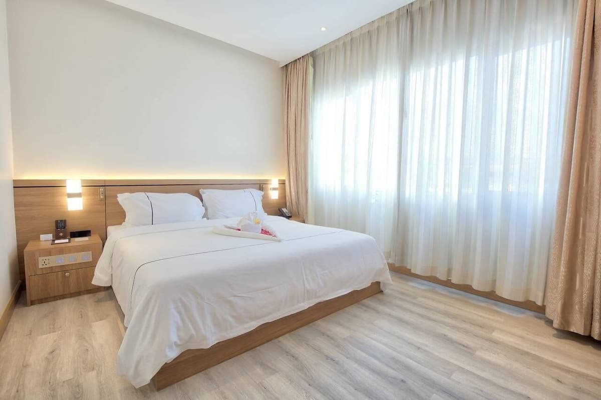 A hotel room with a large bed, a bedside table, and a nightstand.