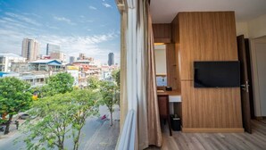 A modern room with a large window, a flat-screen TV, and a view of a cityscape. - Le President Hotel  (Phnom Penh)