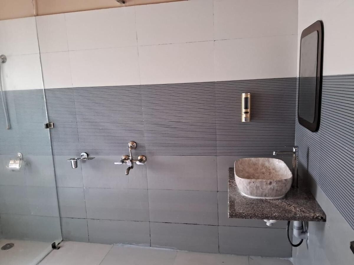 A bathroom with a tiled wall, a sink with a stone basin, and a mirror.