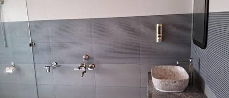 A bathroom with a tiled wall, a sink with a stone basin, and a mirror.