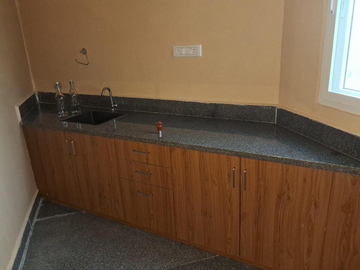 A kitchen with wooden cabinets, a granite countertop, a sink, and a window.