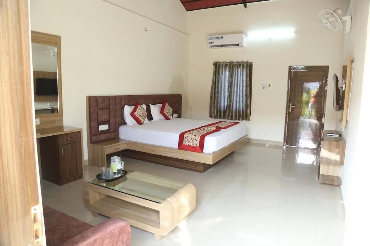 Quarto com cama, mesa de cabeceira, espelho, guarda-roupa e ar condicionado.