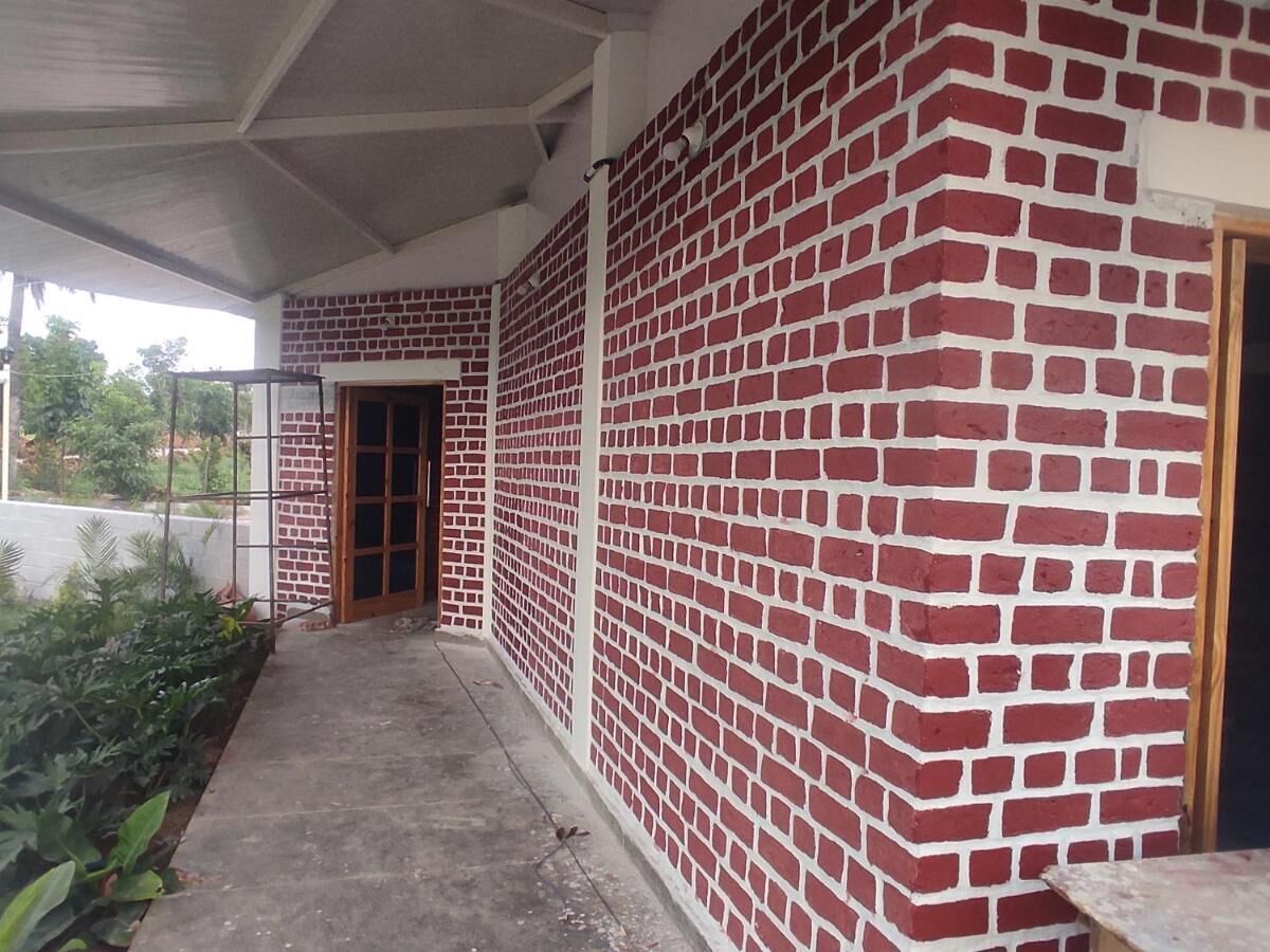 Un edificio con fachada de ladrillo rojo, piso de concreto y una puerta que da a un espacio interior.