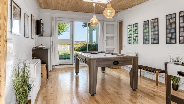 Ein geräumiger Raum mit Billardtisch, Holzboden und Deckenbalken.