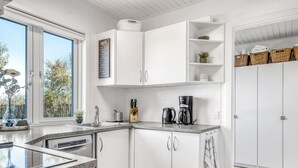 Eine moderne Küche mit weißen Schränken, einer Kaffeemaschine und Blick ins Freie.