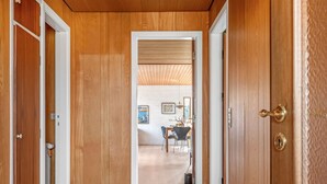 Un pasillo de madera que conduce a un comedor con una mesa y sillas.