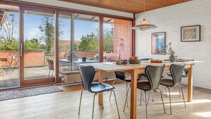 Un comedor moderno con una mesa de madera, sillas negras y una pared de ladrillo blanco.