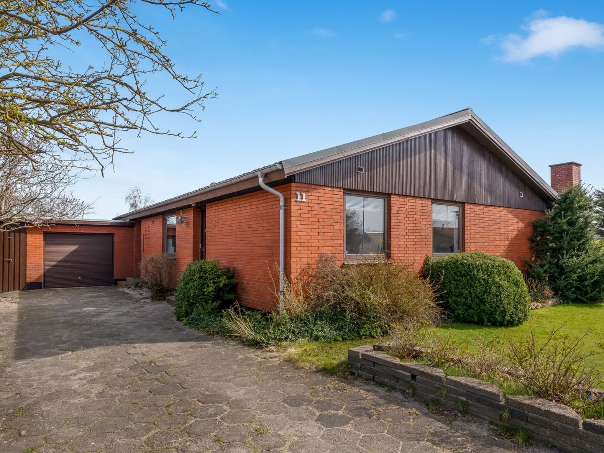 A single-story brick house with a garage, a paved driveway, and a well-maintained lawn.