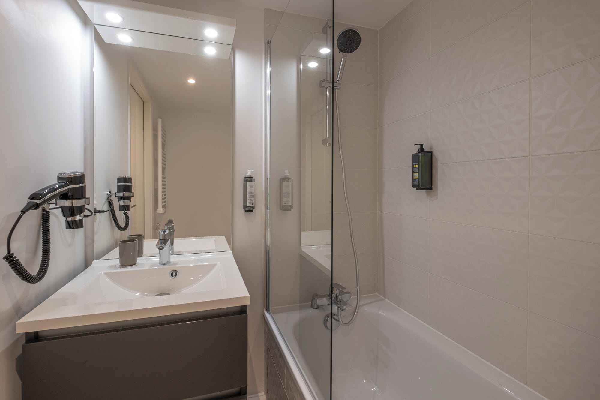 Een moderne badkamer met een douche met glazen wand, een wastafel met dubbele wastafel en een grote spiegel.