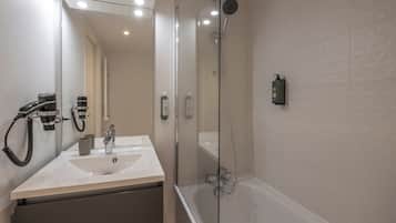Een moderne badkamer met een douche met glazen wand, een wastafel met dubbele wastafel en een grote spiegel.