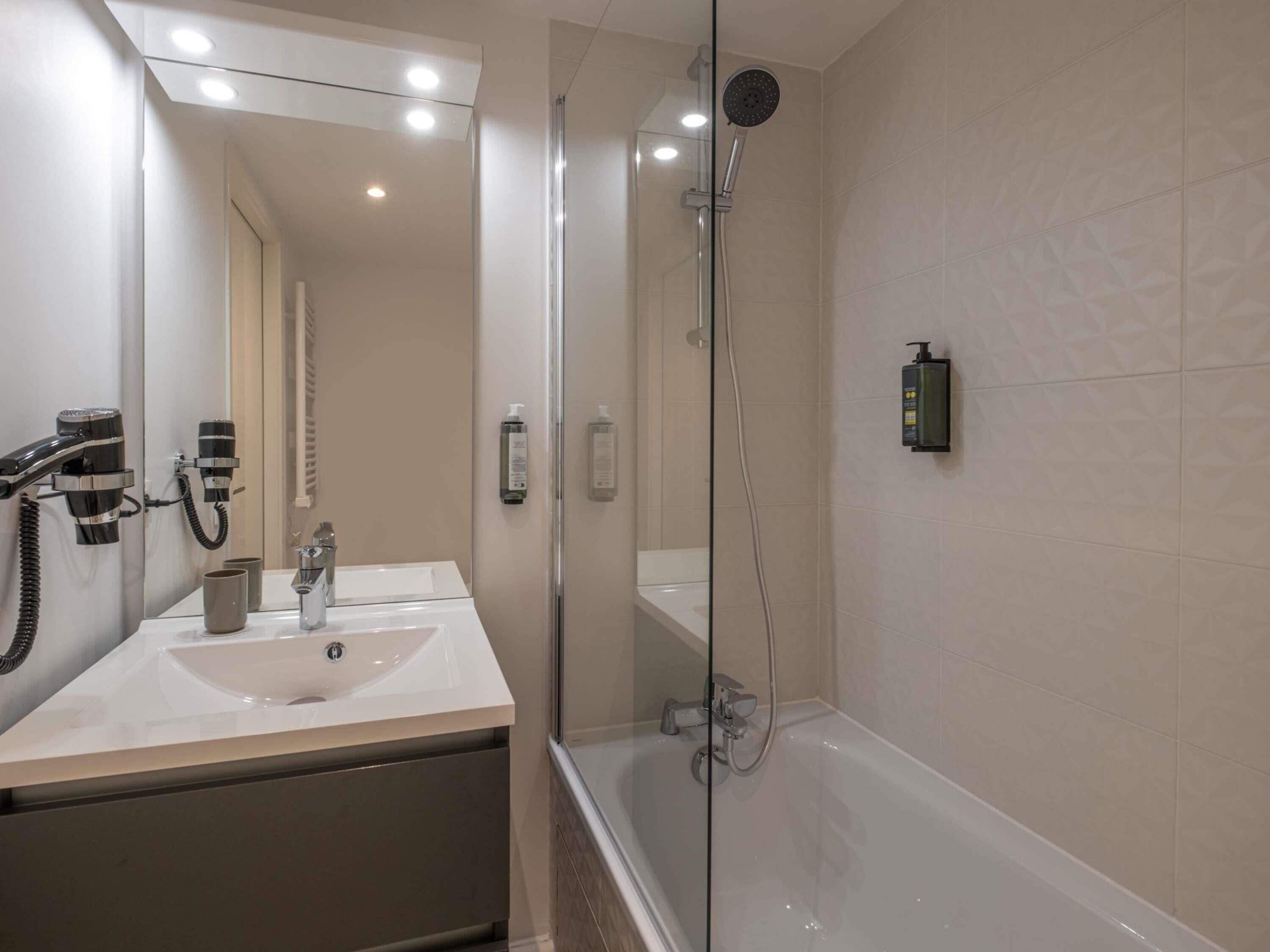 A modern bathroom with a glass-enclosed shower, a white sink, and a mirror above the vanity.