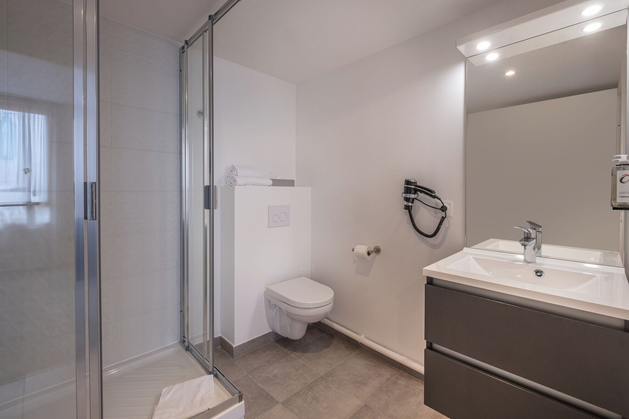 Een moderne badkamer met een douchecabine van glas, een toilet en een wastafel met spiegel.