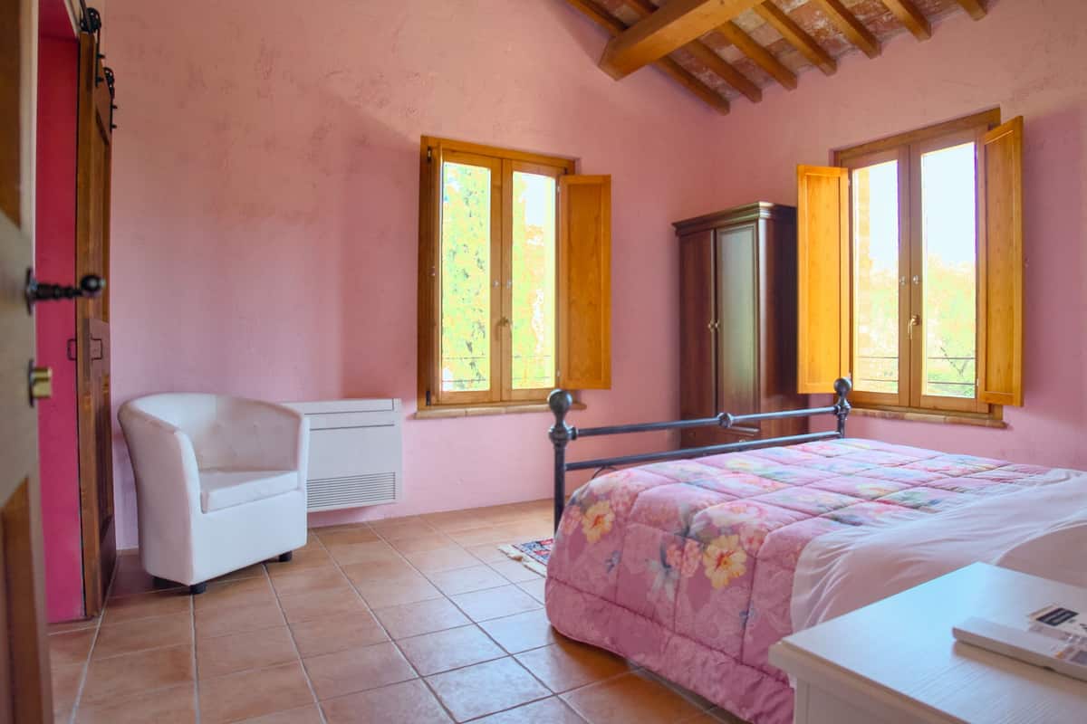 Une chambre à coucher avec un lit, une chaise, une armoire et deux fenêtres.