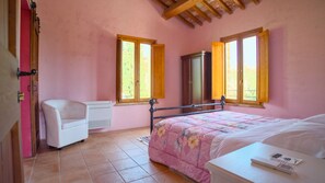 Une chambre à coucher avec un lit, une chaise, une armoire et deux fenêtres.