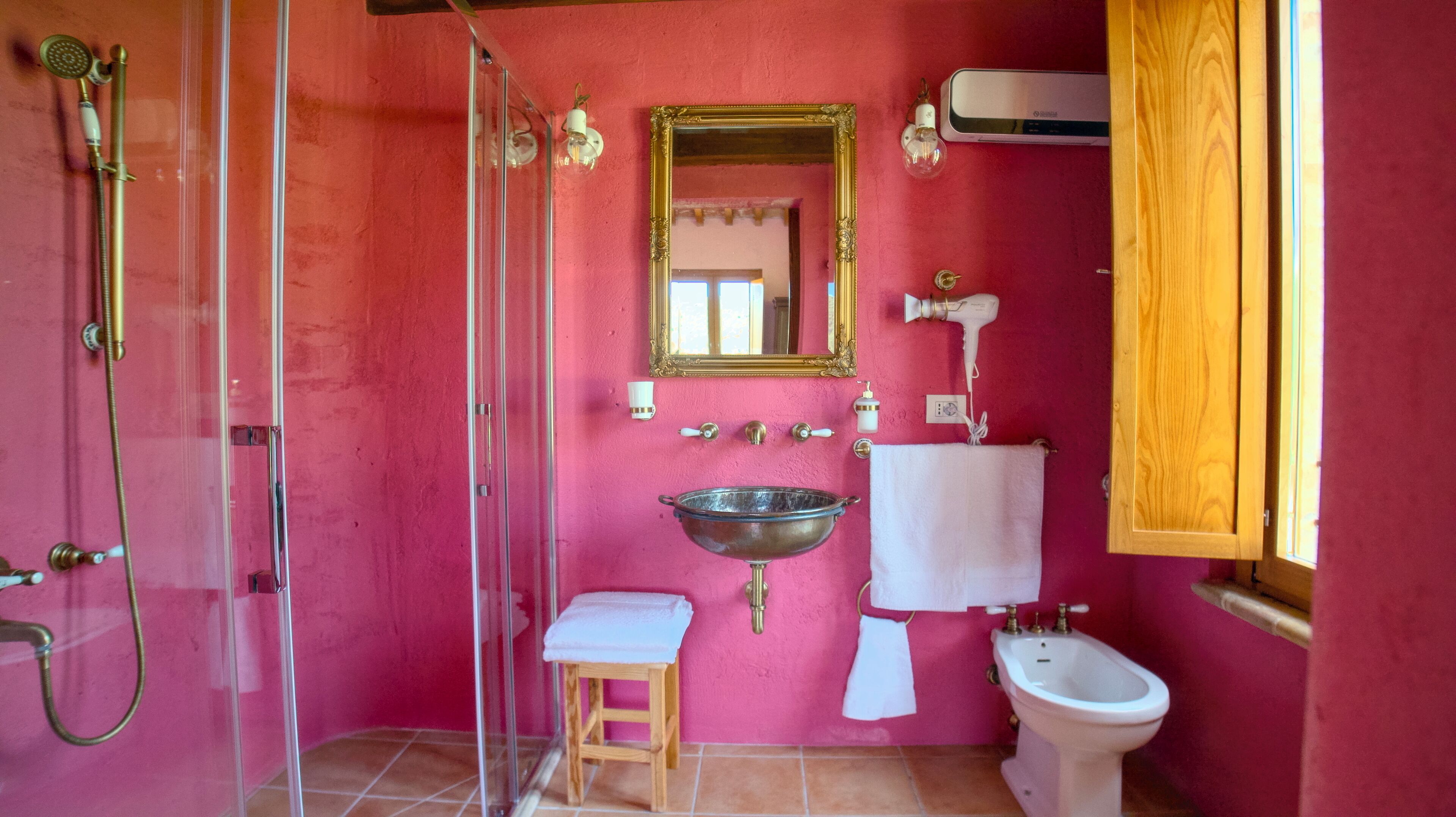 A bathroom with a glass shower enclosure, a sink, a bidet, and a mirror.