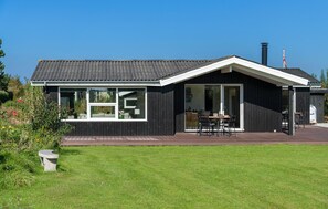 Una casa moderna con una amplia terraza, puertas correderas de vidrio y una chimenea.