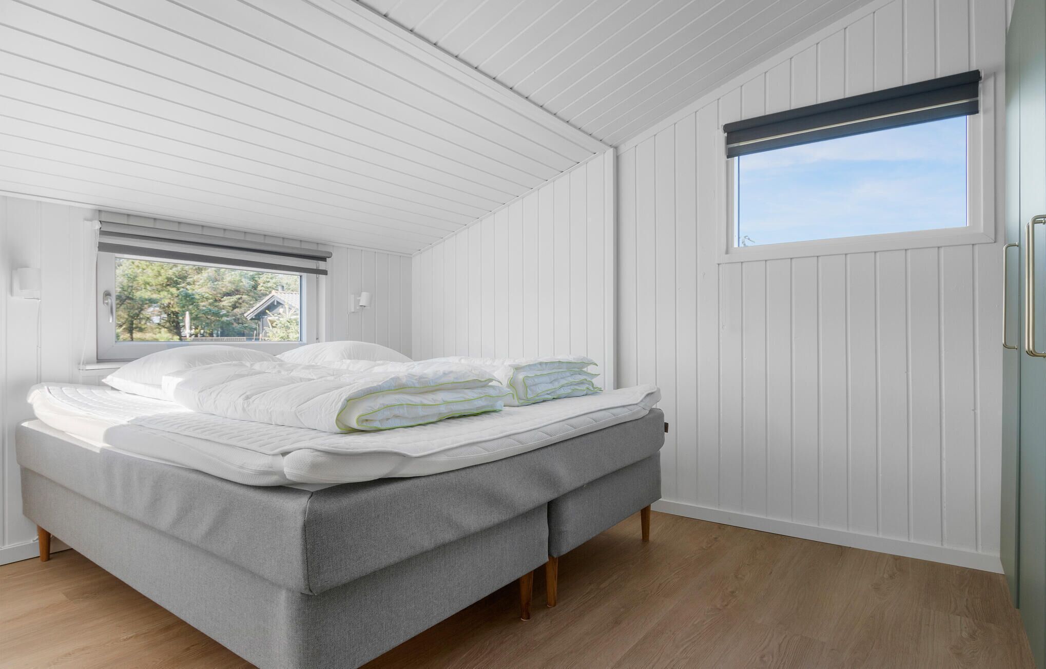 Ein Schlafzimmer mit Bett, Fenster und Holzboden.