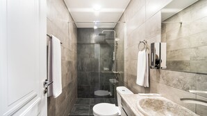 Ein modernes Badezimmer mit einer gläsernen Duschkabine, einer weißen Toilette und einem мрамоrn Waschbecken.