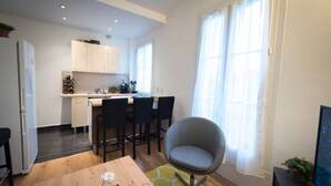 A compact living space with a kitchenette, a dining area with a table and chairs, and a seating area with a chair.