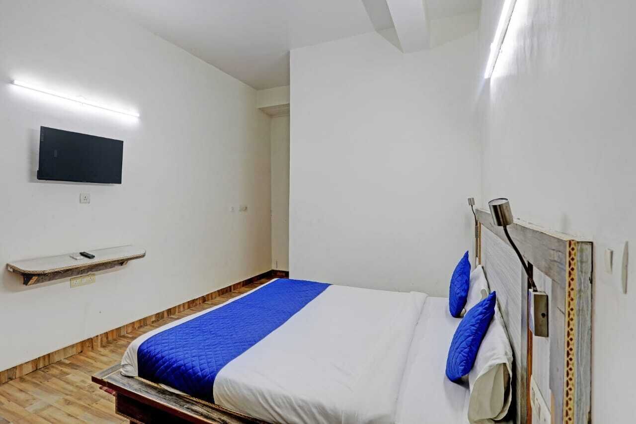 Een slaapkamer met een bed, een tv, een plank en een houten vloer.