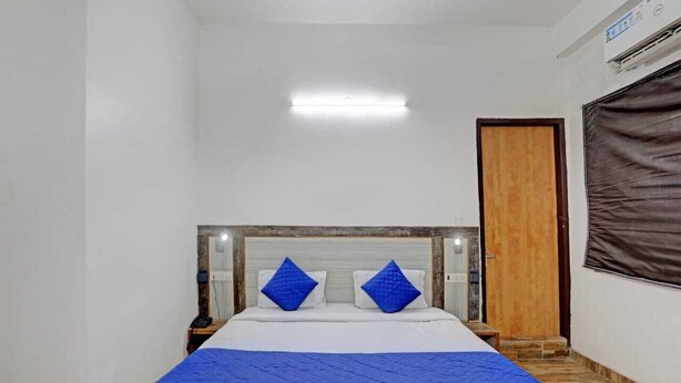 Habitación de hotel con una cama, una mesita de noche, una puerta de madera y una ventana con persiana.