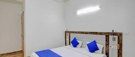 A bedroom with a bed, a nightstand, and a wooden headboard.