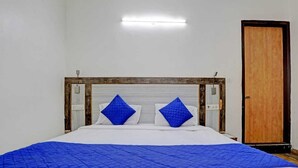 Una cama con colcha azul, ropa de cama blanca y dos almohadas azules.