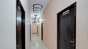 Un pasillo con un cartel que indica depósito, una puerta con manija y un techo con luminarias circulares.