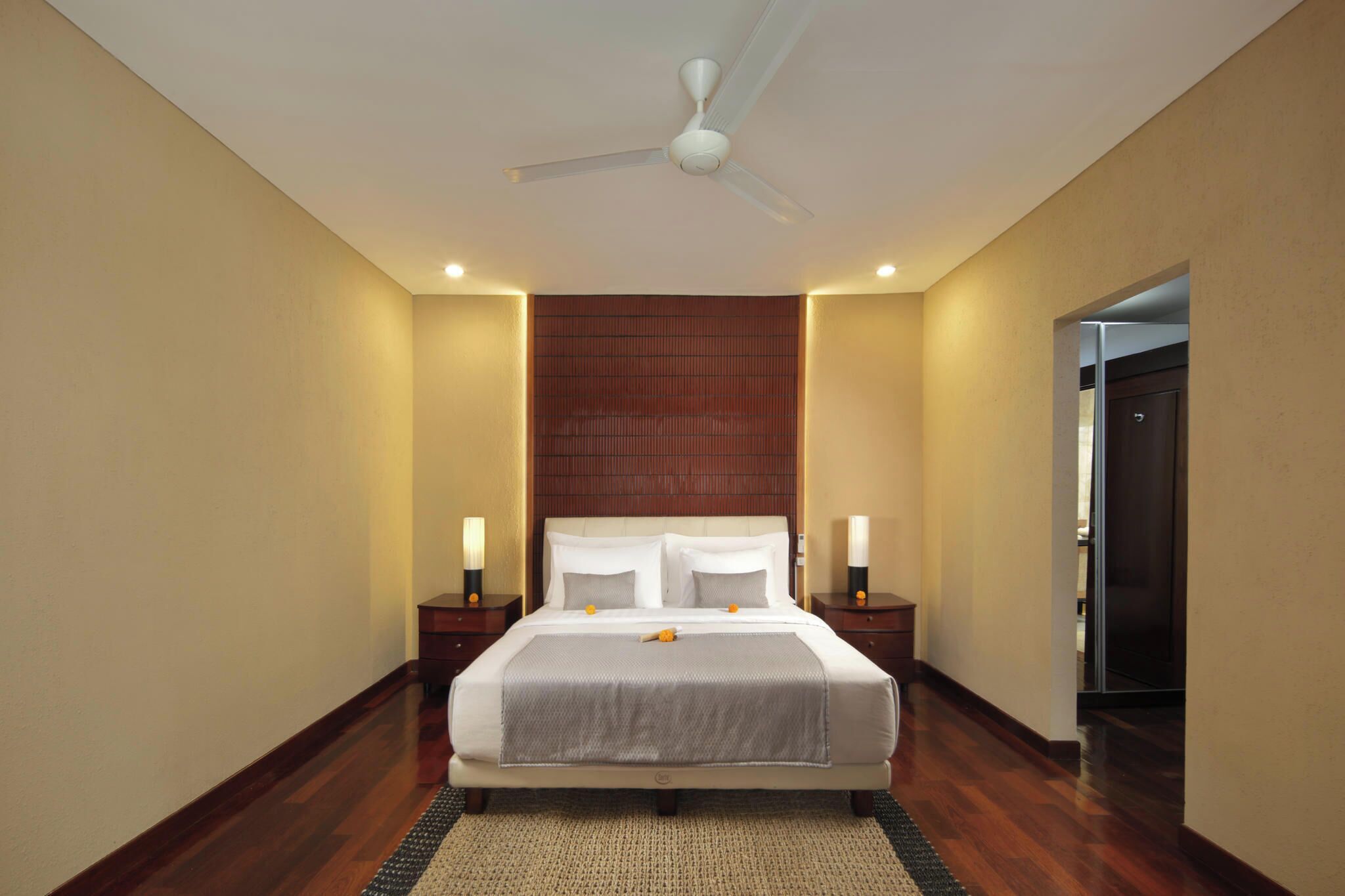 A hotel room with a large bed, a ceiling fan, and two bedside tables with lamps.
