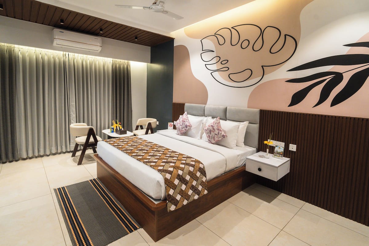 Ein modernes Schlafzimmer mit einem großen Bett, Nachttischen, einem Sessel und einem Wandbild.