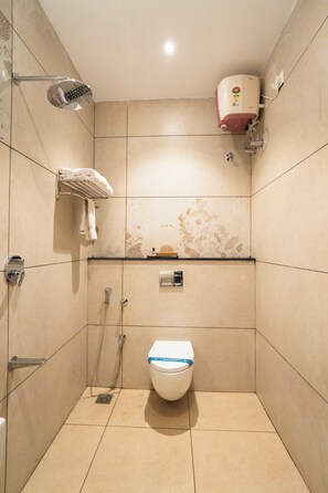 Ein kleines Badezimmer mit Fliesen, Toilette, Dusche und Handtuchhalter.