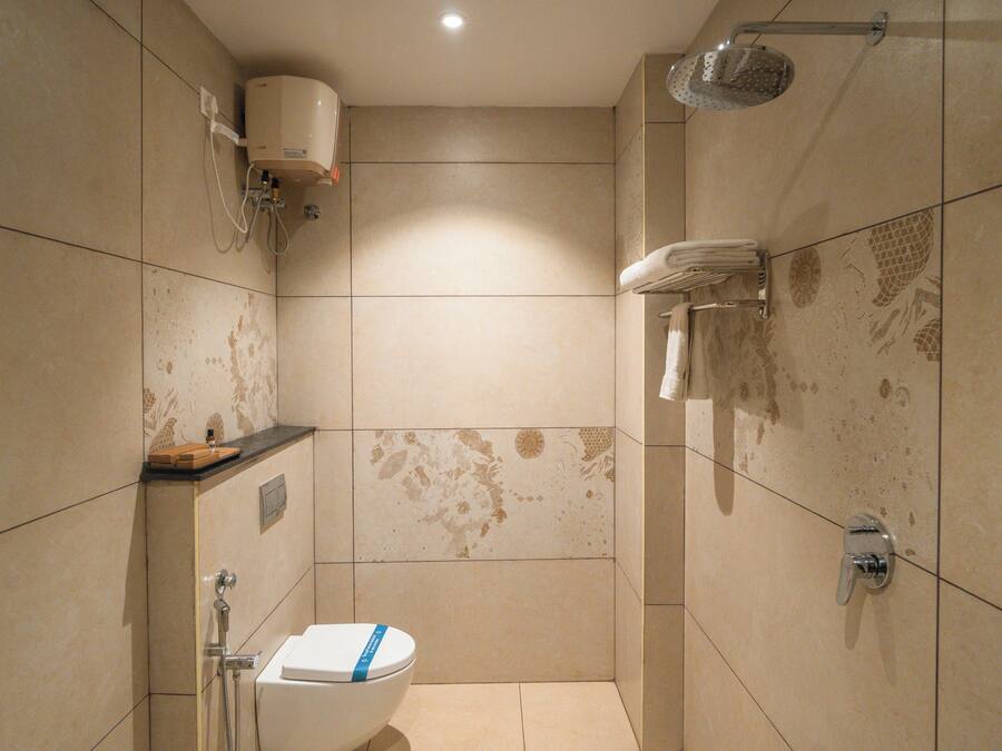 Casa de banho pequena, com azulejos, com sanita, chuveiro e porta-toalhas.