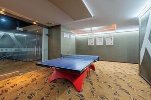 A ping pong table in a room with patterned carpet, a glass partition, and a wall with framed certificates. - Wuhan Huazun Tianlun Hotel (Wuhan)