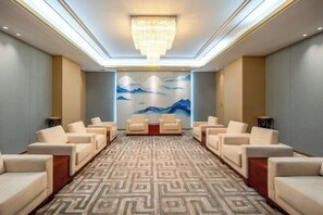Ein Hotelzimmer mit einer großen Chandelüster, einem gemusterten Teppich und einer Wandmalerei.