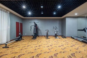 Un gimnasio con equipamiento de ejercicio, una cinta de correr y una alfombra estampada.