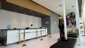 A hotel reception area with a marble counter, a receptionist, and a TV screen. - Jinjiang Inn (Shenzhen Nanshan Science & Technology Park) (Shenzhen)