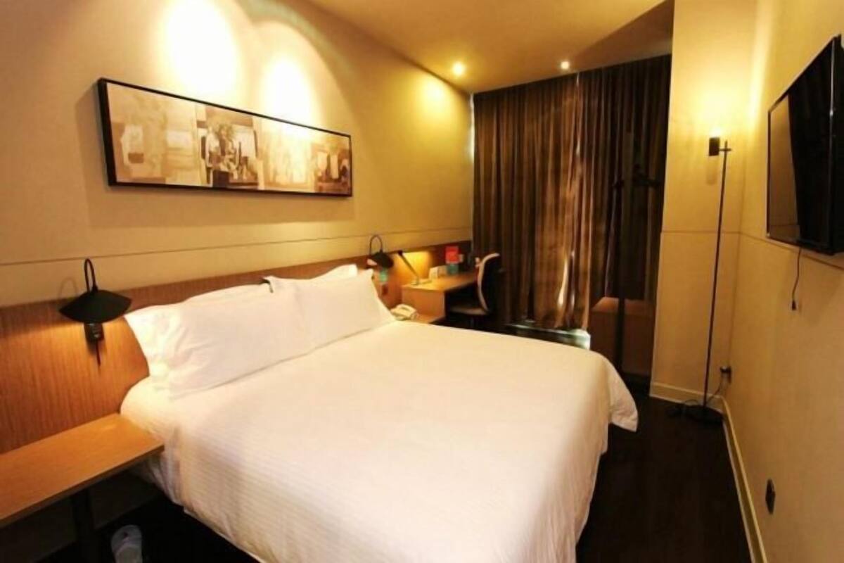 Une chambre d’hôtel avec un lit, une table de chevet, une lampe et un tableau au mur.