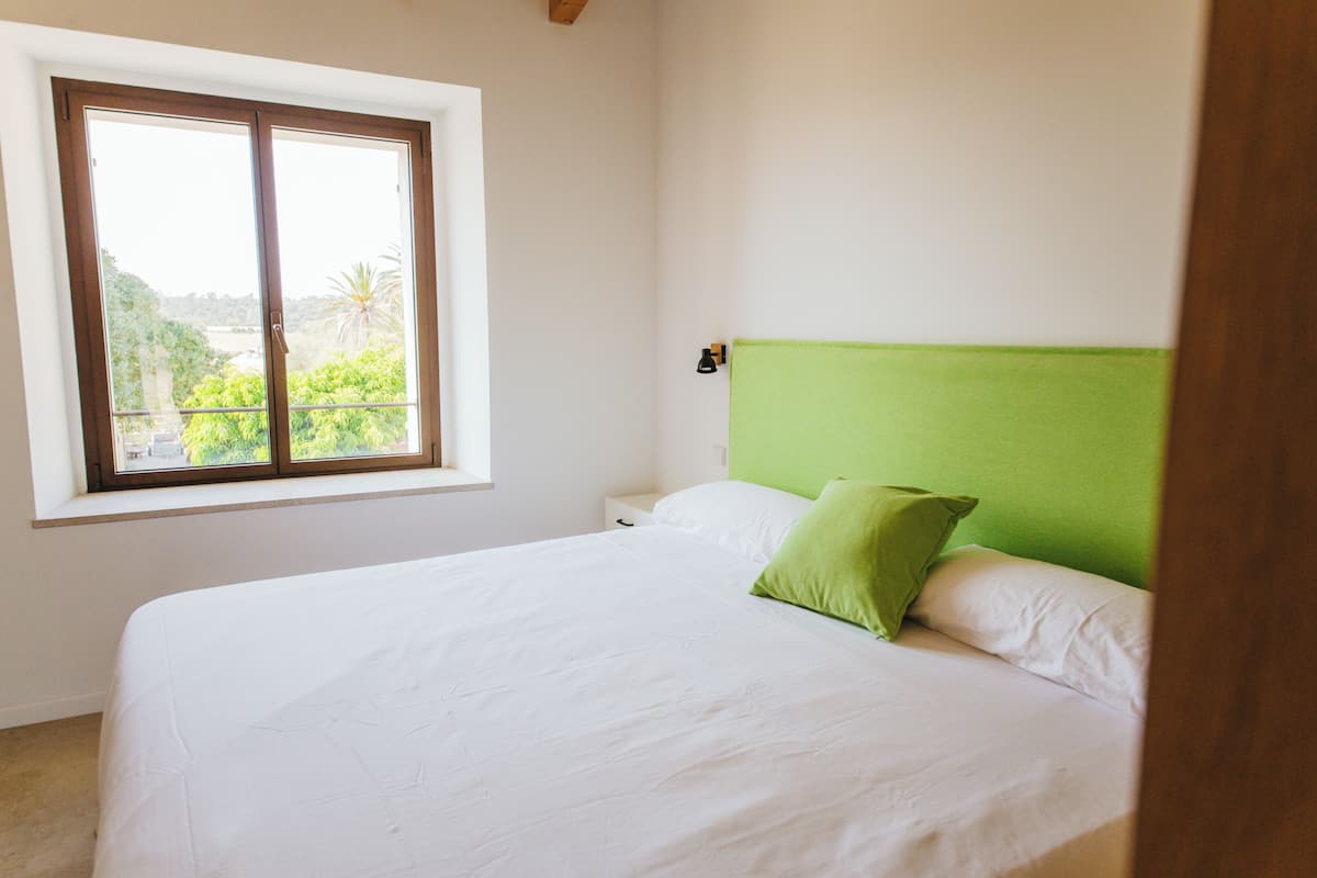 A bedroom with a bed, a window, and a green headboard.
