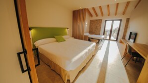 Ein Schlafzimmer mit einem großen Bett, einem Schreibtisch und Blick ins Freie.