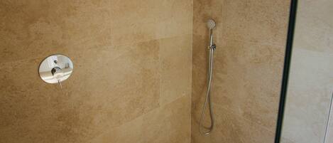 A shower with a handheld showerhead and a wall-mounted faucet.