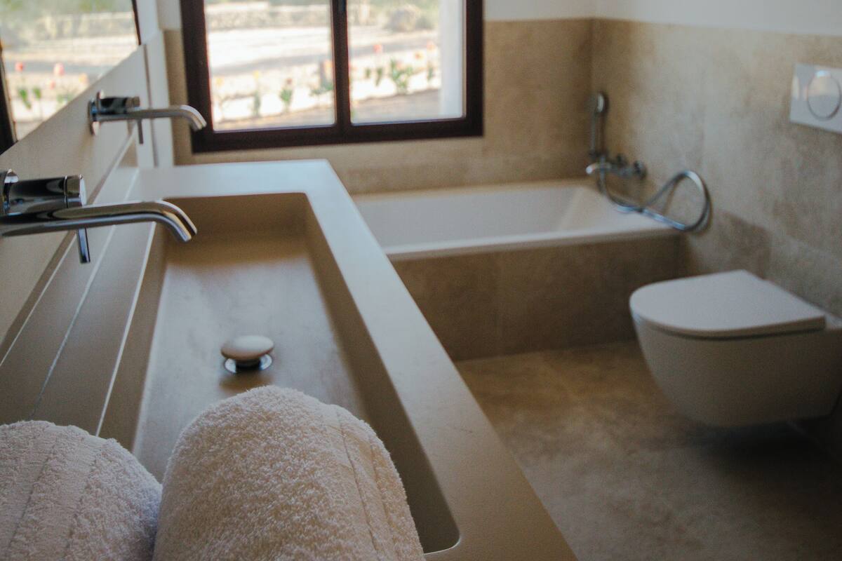 A bathroom with a bathtub, a toilet, and a sink. There is a window providing a view of the outside.