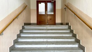 Portaat, joissa on puiset kaiteet, kaksilehtinen ovi, jossa on himmeät lasipaneelit, ja vaaleanvärinen seinä.